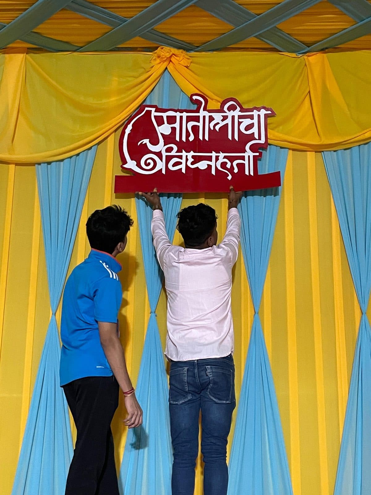 मंडपाच्या पडद्यावर 'मातोश्रीचा विघ्नहर्ता' नामफलक बसवताना — मातोश्री शिवगर्जना गणेशोत्सव २०२४, परेल-भोईवाडा