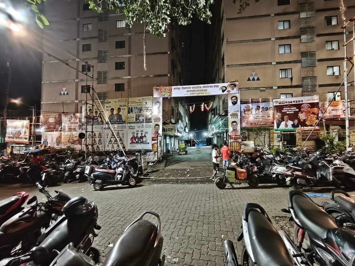 प्रवेशद्वारापासून दिसणारी उजळलेली गल्ली आणि सोसायटीचा परिसर